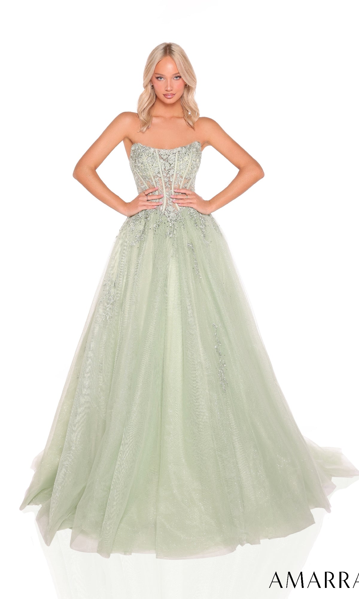 A woman stands against a white background wearing the Amarra 88913 Strapless Long Prom Ball Gown in light green, featuring a fitted embellished bodice and a full tulle skirt.